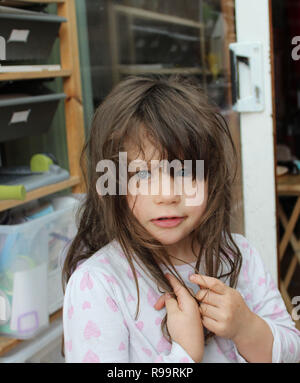 Jeune fille Brunette avec des cheveux bruns dans son pyjama et chocolat autour de la bouche Banque D'Images