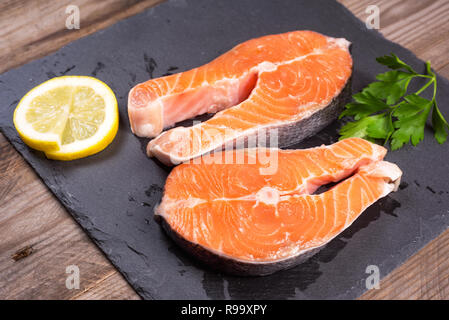 Deux matières premières des darnes de saumon frais avec du citron et du persil sur la table rustique . Banque D'Images