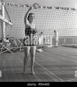 Années 1950, historique, à bord de l'Union européenne-castle steamship 'Kenya', une dame passager dans son maillot à l'extérieur sur la terrasse en bois du navire jouant un jeu de jeter par le net. Banque D'Images