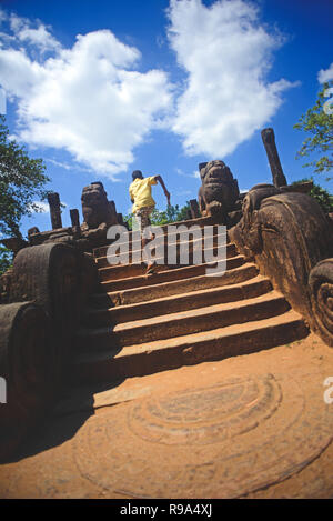 Garçon courir vers le haut des escaliers à, d'une salle d'audience dans la ville antique Polonnaruwa, Sri Lanka Banque D'Images