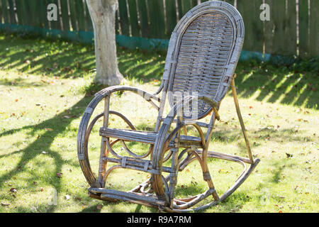 Vieux rocking-chair en osier dans le jardin sur l'herbe Banque D'Images