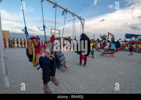 Palu, Central Sulawesi, Indonésie. 22 Décembre, 2018. Les enfants victimes du tremblement de jouer sur l'aire de jeux avec l'aide d'un organisme humanitaire international dans le camp de réfugiés d'Balaroa. Les installations et l'infrastructure dans les camps pour les victimes de catastrophes d'alléger le fardeau des résidents touchés par le séisme, le tsunami et la liquéfaction de Palu, Sigi et Donggala survenue le 28 septembre 2018. Credit : bmzIMAGES/Alamy Live News Banque D'Images