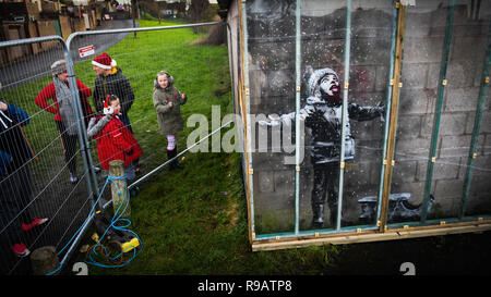 Port Talbot, Pays de Galles, Royaume-Uni. 22 Décembre 2018 Une œuvre de célèbre artiste de rue, Banksy, a été recouverte d'une couverture de protection en plastique, dans la Galles du sud ville de Port Talbot. L'art, montre un enfant se couvrir de cendres d'un bac de gravure et a attiré des milliers de visiteurs depuis en a été confirmée comme étant l'accomplissement de l'artiste, Bristol l'action de l'OMS a atteint des centaines de milliers de livres aux enchères. Crédit photo : Robert Melen/Alamy Live News Banque D'Images