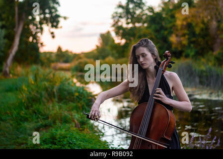 Le violoncelliste femelle joue dans le parc Banque D'Images