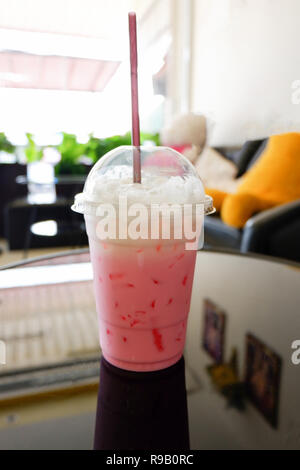 Lait fraise shake Rose / Rose glacé Lait dans tasse en plastique et de la paille sur la table d'un café Banque D'Images