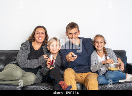 Jeune famille regardant la TV à l'intérieur. Vue de face des gens assis sur le canapé en regardant la télévision. Banque D'Images