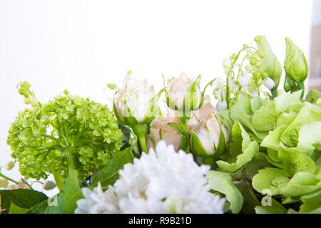 Un grand nombre de yety, un grand bouquet de luxuriant snowdrop, de rose, de pivoine et de Bell avec les verts dans un grand vase transparent élégant long sur la jambe sur un wh Banque D'Images