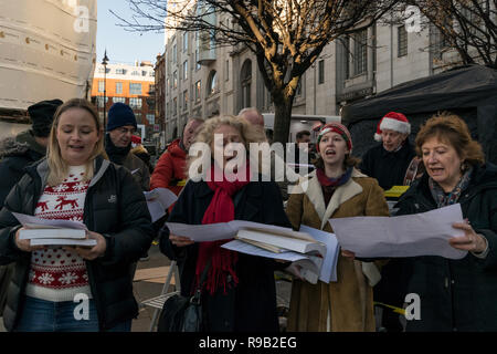 Un groupe d'hommes et de femmes le chant de Noël sur la rue dans le centre de Londres, en décembre 2018, au Royaume-Uni. Banque D'Images