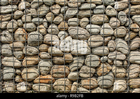 Mur de pierres rondes, fixée avec un fil de fer en acier (net) de gabions de pierre Banque D'Images