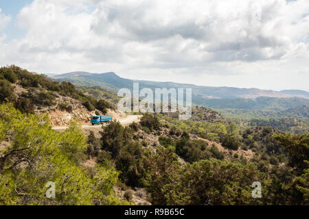 Petit camion bleu roulant sur une petite route de gravier et sinueuse dans péninsule d'Akamas, à Chypre. Banque D'Images