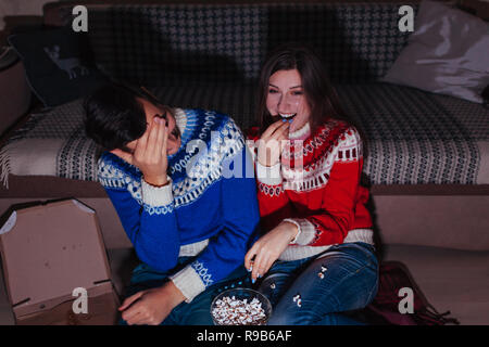 Jeune couple regarder film comique eating popcorn at home la nuit. Rire de la famille Banque D'Images