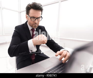 Vérification des comptes d'affaires graves alors qu'il était assis à son bureau. Banque D'Images