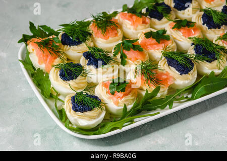 Oeufs farcis au saumon et caviar décoré par le persil et l'aneth. Cuisine de fête Banque D'Images