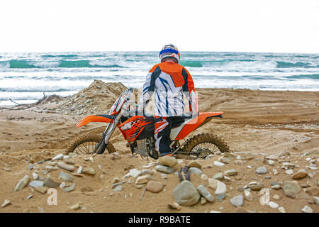 Motocycliste dans un vêtement de protection assis sur moto en face de la mer Banque D'Images