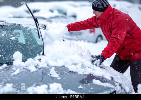 Problèmes d'hiver des automobilistes. Un homme se brosser la neige de la voiture. Jeune homme l'enlèvement de la neige à partir de la voiture. Banque D'Images