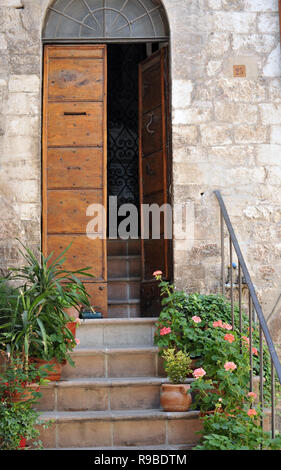 Porte ouverte sur une maison à Assisi, Italie avec des fleurs dans l'escalier Banque D'Images