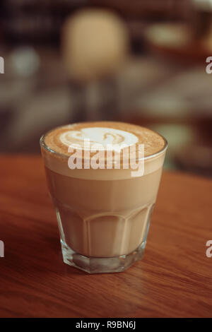 Cappuccino ou café blanc sèche-servi dans un petit verre sur la table d'un café en tourné avec copy-space Banque D'Images