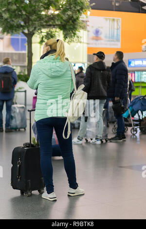 Jeune femme avec un bagage à main dans l'aéroport international terminal, à la recherche d'information au conseil, contrôler son vol. fille avec une valise à l'aéropo Banque D'Images