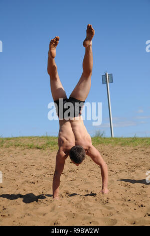 Kovrov, la Russie. 12 juillet 2014. Quartiers de la ville, le lac de Kovrov Starka (Krivoe). Teen doing handstand sur la plage du lac Banque D'Images