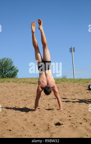 Kovrov, la Russie. 12 juillet 2014. Quartiers de la ville, le lac de Kovrov Starka (Krivoe). Teen doing handstand sur la plage du lac Banque D'Images