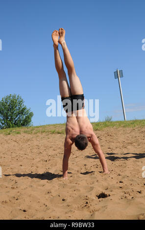 Kovrov, la Russie. 12 juillet 2014. Quartiers de la ville, le lac de Kovrov Starka (Krivoe). Teen doing handstand sur la plage du lac Banque D'Images