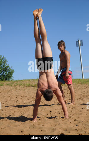 Kovrov, la Russie. 12 juillet 2014. Quartiers de la ville, le lac de Kovrov Starka (Krivoe). Teen doing handstand sur la plage du lac Banque D'Images