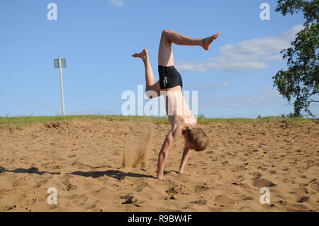 Kovrov, la Russie. 12 juillet 2014. Quartiers de la ville, le lac de Kovrov Starka (Krivoe). Teen doing handstand sur la plage du lac Banque D'Images