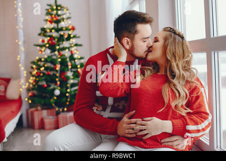 Cute family sitting near Christmas Tree Banque D'Images