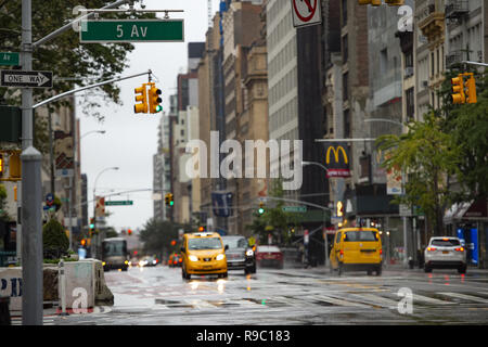 Les voitures et les taxis relient la 5e avenue sur un jour froid et pluvieux. Manhattan, New York City, United States. Banque D'Images