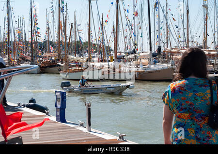 Port de Yarmouth, île de Wight, festival Old Gaffers 2012. Beaucoup de voiliers, drapeaux soufflant sur des mâts, vue arrière de femme regardant dehors. Été. Banque D'Images
