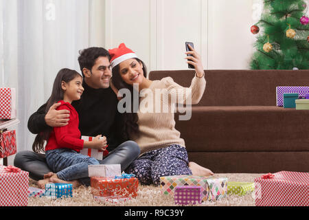 Famille heureuse utiliser Smart phone pour prendre les célébrations de Noël sur selfies Banque D'Images