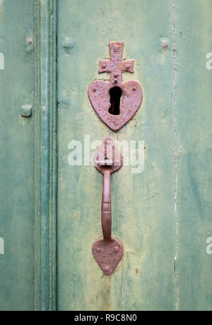 Vintage keyhole et poignée de porte avec un coeur et croix dans une vieille porte. Banque D'Images