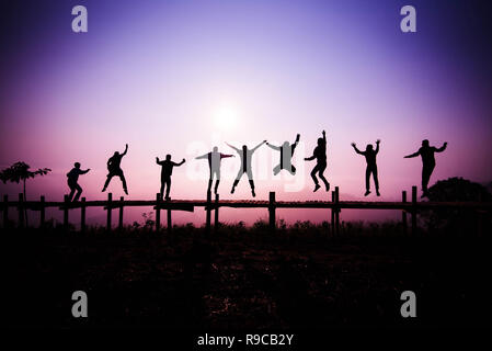 L'équipe de Jumping Silhouette / les amis de sauter sur le pont de bois sur la colline - profitez de joyeuse et amusante avec les gens de saut du lever ou du coucher du soleil dans la maison de vacances Banque D'Images