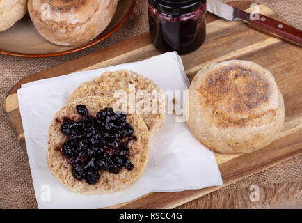 Vue aérienne d'un muffin anglais couper en deux et tartiner avec blueberry conserve sur une serviette avec un ensemble de muffin et pot de conserve Banque D'Images