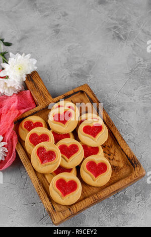 Les cookies en forme de coeur rempli de fleurs de chrysanthèmes sur une planche de bois. Close-up. Concept pour la Saint-Valentin. Banque D'Images