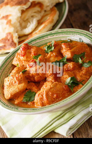 Karhai poulet dans une sauce tomate épicée libre servi avec du pain naan sur une table verticale. Banque D'Images