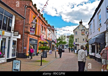 Les gens se promener le long de la rue principale de Sidmouth, Devon, dans une rue calme sunny aftenoon. Jolie bunting et fleurs faire la rue pittoresque. Banque D'Images