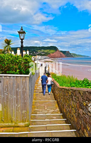 Un couple marche dans le sentier du littoral menant à la pittoresque ville côtière de Sidmouth dans le Devon, avec des falaises de la côte jurassique. Banque D'Images
