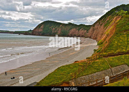 Les falaises de grès rouge de la côte jurassique à l'ouest de la station balnéaire de Sidmouth.les uns flânant le long du littoral sur une journée nuageuse. Banque D'Images