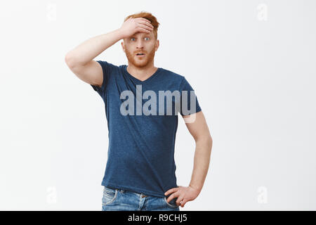 Ça alors, si proche. Portrait de Guy de venir au sens soulagé après choc nerveux et sentiments, essuyant la sueur du front, la fixant avec des yeux à sauté, caméra tenue main sur mur gris taille plus Banque D'Images