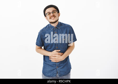 Les jeunes en difficulté manger nourriture avariée guy holding hands on belly souffrant de maux de dents serrées en attente près de toilettes publiques dans la file d'attente debout avec des sentiments douloureux sur fond blanc Banque D'Images