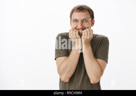 Impatient funny guy européenne ayant des dépendances et en attente de résultats pour pari mordant nerveusement les ongles et souriant avec excité et heureux à l'expression avec l'appareil photo d'oeil Fou Banque D'Images