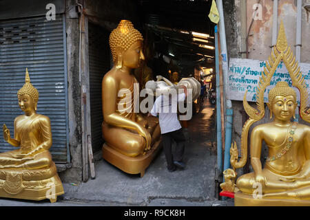 Dans une usine de statues de Bouddha en Bamrung Muang Road, Bangkok, Thaïlande, l'employé est une statue à moitié terminé, en passant d'autres statues de Bouddha Banque D'Images