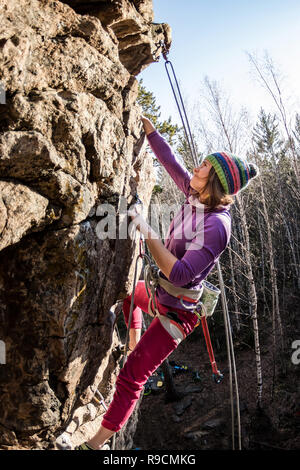 Girl rock climber grimpe sur le rocher avec la réduction de la prime d'hommes dans des vêtements colorés et un chapeau à l'automne Banque D'Images