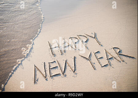 Bonne année message écrits en sable lisse et propre avec une nouvelle vague à la plage Banque D'Images