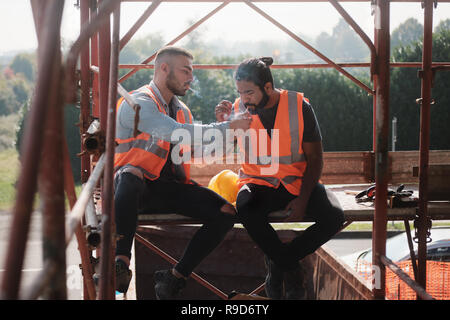 Les travailleurs de la construction et de cigarette en conversation sur pause Banque D'Images