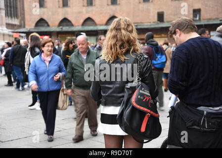 Un hipster girl en marchant dans la rue à Bologne avec son petit ami. Sur l'arrière-plan un couple alderly. Bologne, Italie Banque D'Images