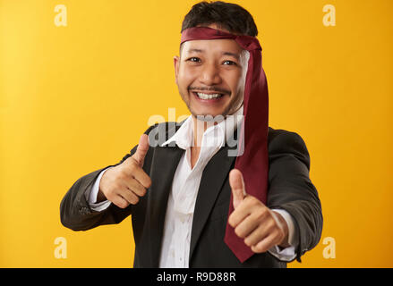 Guy asiatique ivre avec cravate sur fond de couleur jaune Banque D'Images