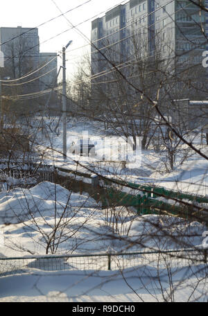 Kovrov, la Russie. 23 janvier 2016. Vue sur le jardin de devant de la vieille maison de bois d'un étage et de rue avec des bâtiments à plusieurs étages en th Banque D'Images