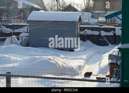 Kovrov, la Russie. 23 janvier 2016. Cour intérieure de l'histoire unique vieille maison de bois dans l'ensoleillée frosty day. Garage pour voiture et moto Transports Banque D'Images